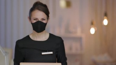 Koronavirüs salgını sırasında iş. Modern güzellik salonunda ffp2 maskeli ve açık tabelalı bir kadın..