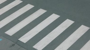 Beyaz eşofmanlı, iş kitabı, sırt çantası ve kulaklığı olan, yaya geçidinden geçen ve açık havada okula giden son moda öğrencinin üst görüntüsü..