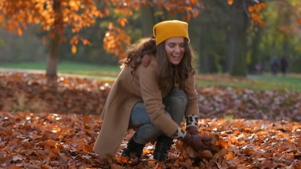 茶色のコートを着た40歳の女性と秋に街の公園で屋外で楽しむ黄色の帽子を笑顔 このビデオはPror422コーデックで作られました — ストック動画