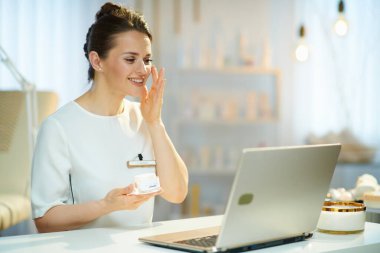 Bilgisayarlı mutlu kadın işçi modern güzellik stüdyosunda sanal toplantı yapıyor..