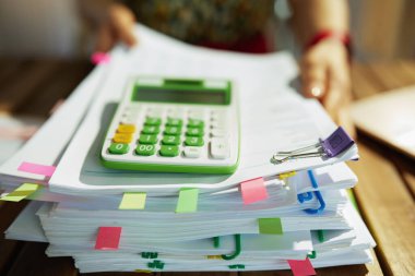 Vergi zamanı. Ofisinde doküman ve hesap makinesi olan modern muhasebeci kadına yakın çekim..