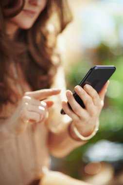 Yeşil Ev. Güneşli bir günde orta yaşlı bir kadının oturma odasında akıllı telefon uygulamaları kullanarak yakın plan çekimleri..