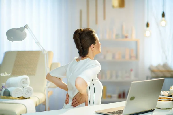 Müde Arbeiterin Mit Laptop Mit Rückenschmerzen Modernem Schönheitssalon — Stockfoto