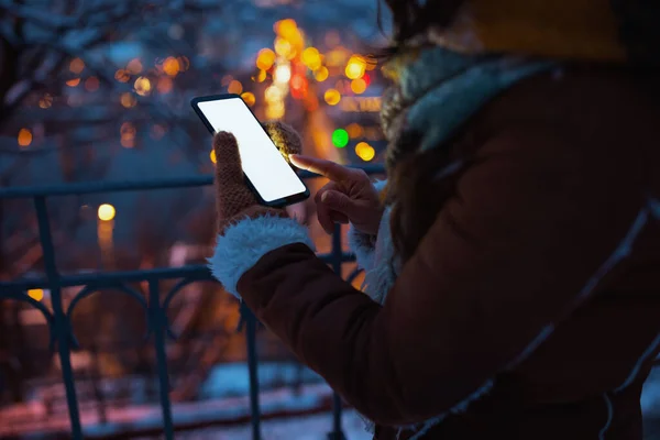 夜はスマートフォンアプリを使って 冬のシープスキンコートで街の公園の女性の屋外での閉鎖 — ストック写真