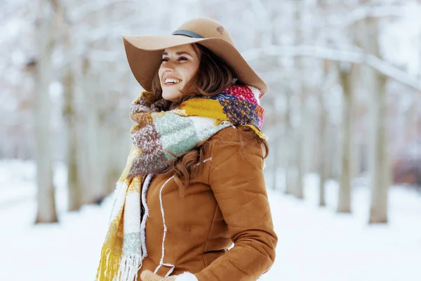 穿着羊皮外套的现代女性穿着棕色的帽子和围巾 站在城市公园的室外微笑 — 图库照片