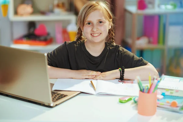 ポートレートの笑顔現代的な女の子でグレーシャツとともにラップトップとワークブックホームスクールで自宅で晴れた日 — ストック写真