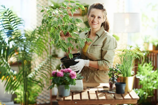 リラックスした家庭菜園 幸せな現代女性の肖像画白いゴム手袋で鉢植えの植物で日当たりの良い日のモダンなリビングルーム — ストック写真