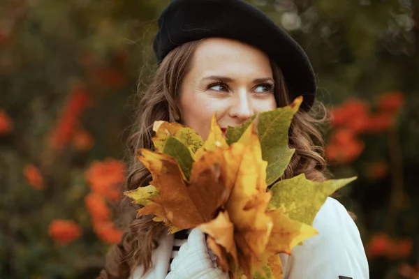 11月だ ベージュトレンチコートを着た若い女性と秋に街の通りの外で黄色の葉と黒ベレー帽 — ストック写真