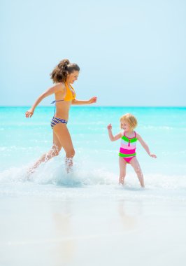 Deniz kıyısında oynayan anne ve bebek kız