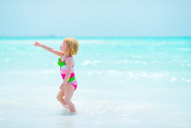 Kopya alanı deniz kıyısında işaret eden kız bebek