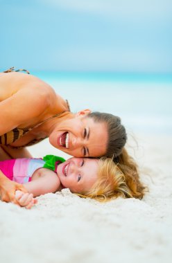 Kumsalda oynarken anne ve bebek kız portresi