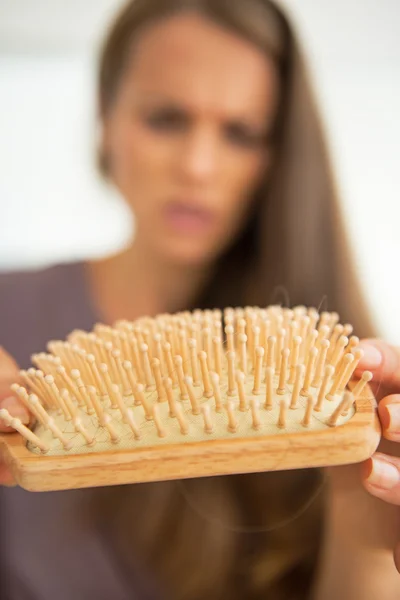 Primer plano de la mujer preocupada mirando en peine de pelo — Foto de Stock