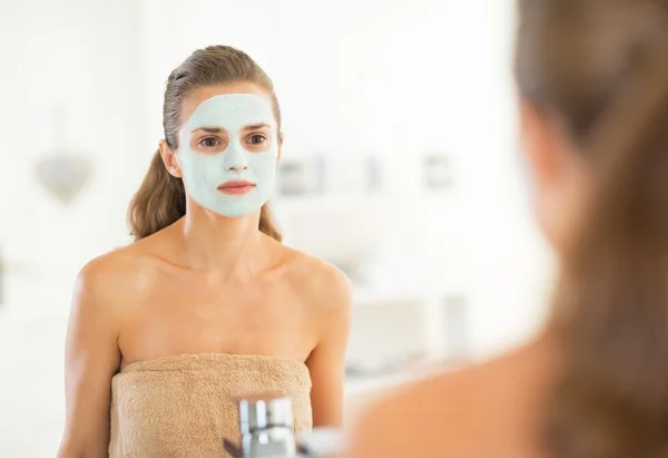 Retrato de mulher jovem com máscara cosmética facial olhando em mir — Fotografia de Stock