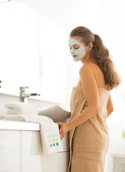 Młoda kobieta ubrana twarzy maski kosmetyczne w łazience — Zdjęcie stockowe