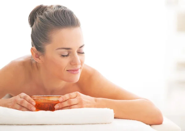 Young woman laying on massage table with honey plate — Stock Photo, Image