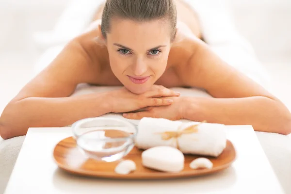 Young woman laying on massage table near spa therapy ingredients — Stock Photo, Image