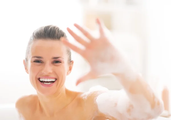 Retrato de mujer joven y feliz en la bañera mostrando espuma —  Fotos de Stock
