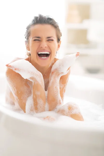 Glückliche junge Frau spielt mit Schaum in Badewanne — Stockfoto