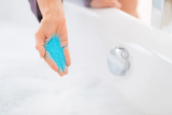 Primer plano de la mujer joven añadiendo sal de baño en la bañera — Foto de Stock