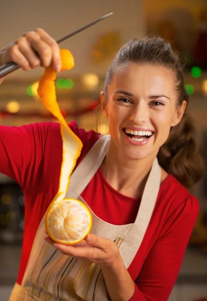 Porträt einer lächelnden jungen Hausfrau, die Orangenhaut entfernt — Stockfoto