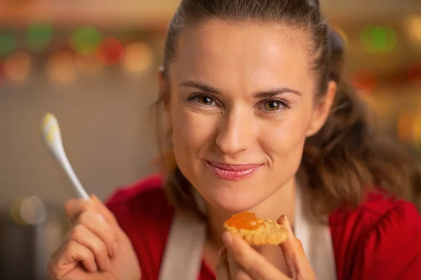 Retrato de feliz jovem dona de casa comendo compota de laranja caseira — Fotografia de Stock