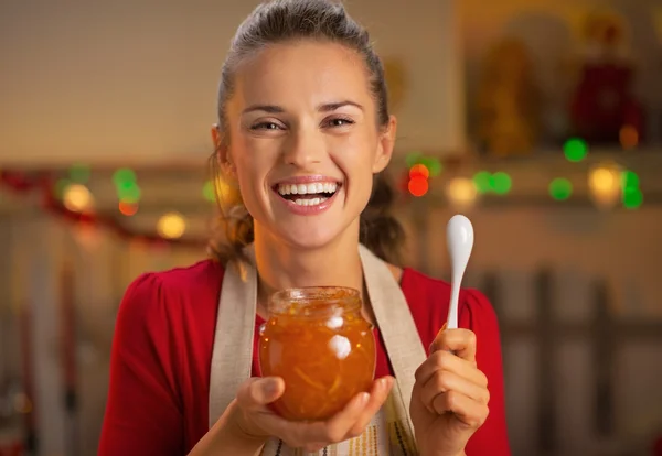 Retrato de feliz joven ama de casa sosteniendo mermelada de naranja — Foto de Stock