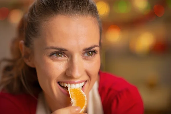 Portret van jonge huisvrouw eten oranje — Stockfoto