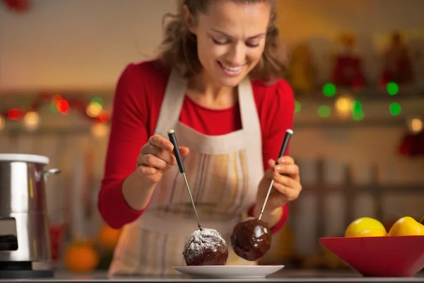 Glückliche junge Hausfrau macht Apfel in Schokoglasur — Stockfoto