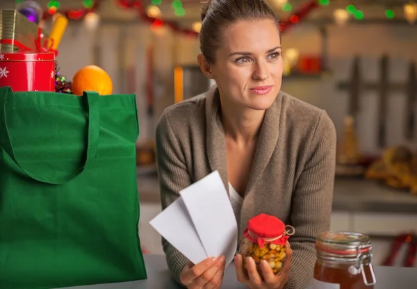 Thoughtful young housewife with christmas shopping bag and check — Stock Photo, Image