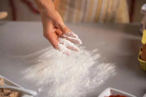 Gros plan sur la jeune femme au foyer saupoudrer de farine sur la table — Photo