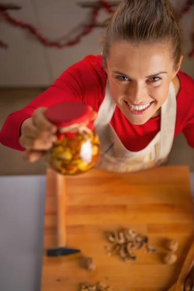 Retrato de feliz jovem dona de casa mostrando frasco com mel nozes — Fotografia de Stock