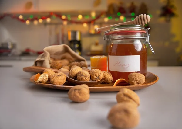 Detailní záběr na vlašské ořechy a sklenice medu na stole — Stock fotografie