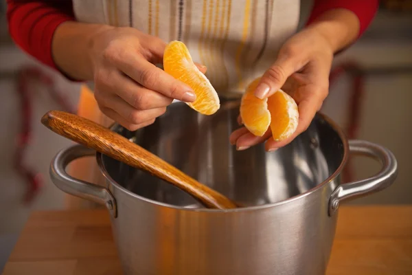 Gros plan sur la jeune femme mettant des tranches d'orange dans la casserole — Photo