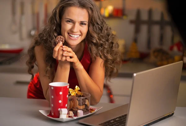 Jovem dona de casa feliz com lanches de Natal usando laptop em kitc — Fotografia de Stock