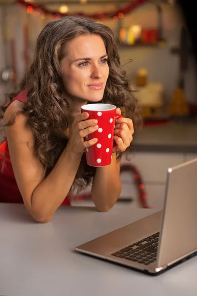 Pensée jeune femme au foyer avec tasse de chocolat chaud à l'aide de lapto — Photo