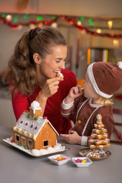 Mãe feliz e bebê comer biscoito no Natal decorado kitch — Fotografia de Stock