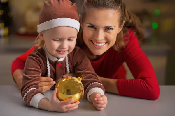 Retrato de la madre sonriente y el bebé sosteniendo la bola de Navidad —  Fotos de Stock