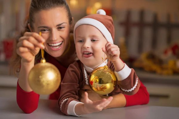 Retrato de mãe sorridente e bebê segurando bolas de Natal — Fotografia de Stock