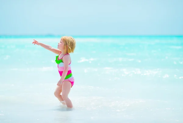 Meisje van de baby wijzen op kopie ruimte op Zeekust — Stockfoto