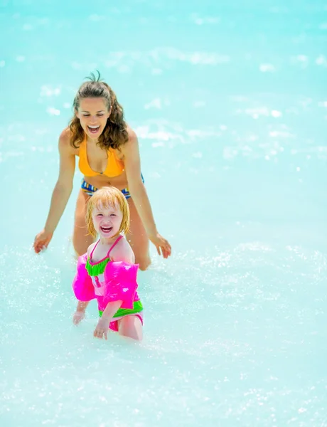 Gelukkig moeder en babymeisje spelen in zee — Stockfoto