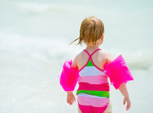 Baby girl going into sea. rear view — Stock Photo, Image