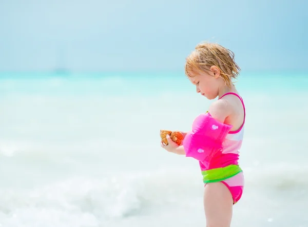 Portret van babymeisje houdt van shell op strand — Stockfoto