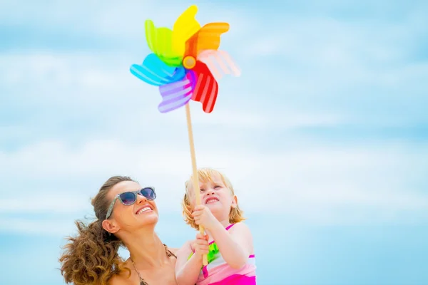 Happy mother and baby girl holding colorful windmill toy — Stock Photo, Image