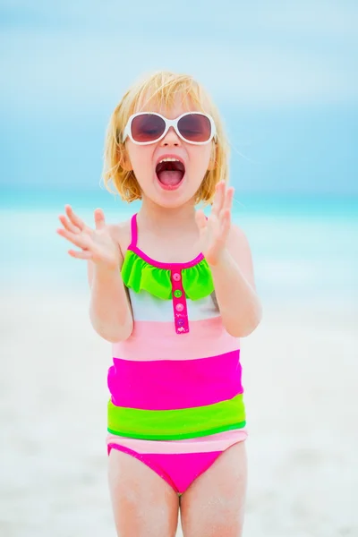 Portret van vrolijke babymeisje in zonnebril op strand — Stockfoto