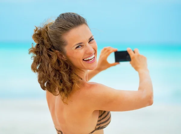 Usměvavá mladá žena s foto na pláži — Stock fotografie