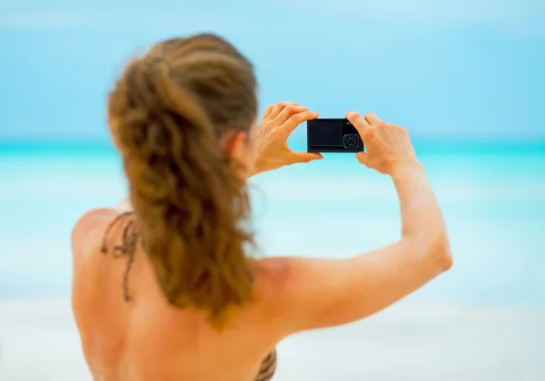 Ung kvinna ta foto på stranden. bakifrån — Stockfoto