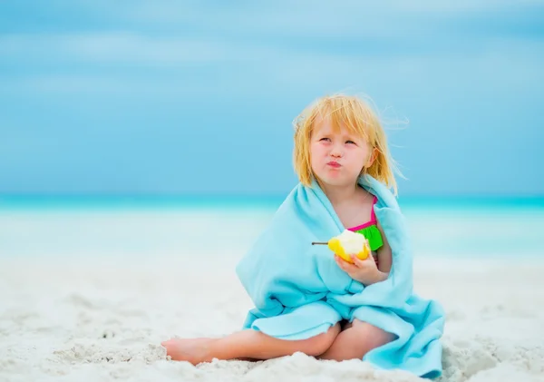 Portrait of baby girl eating pear on beach — Stock Photo, Image