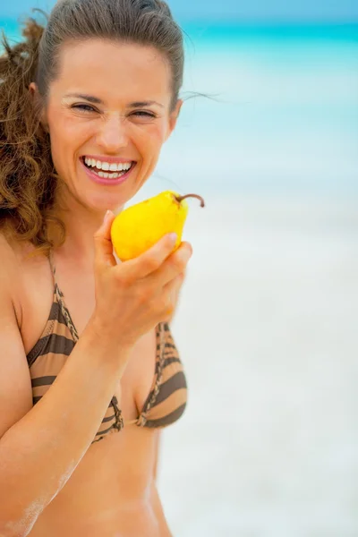 Ritratto di giovane donna felice che mangia pera sulla spiaggia — Foto Stock