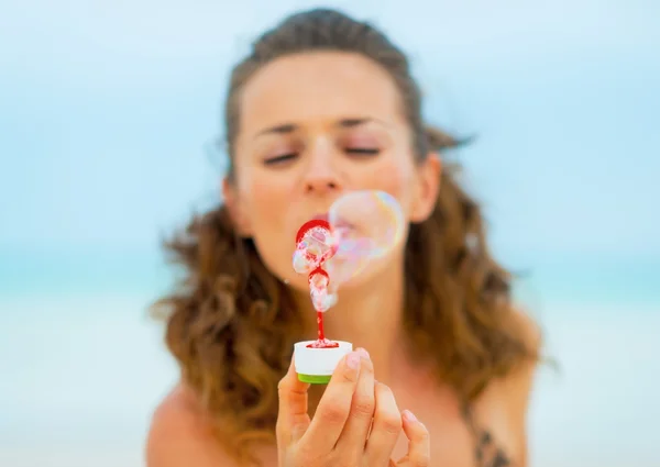 Gros plan sur jeune femme soufflant des bulles de savon sur la plage — Photo