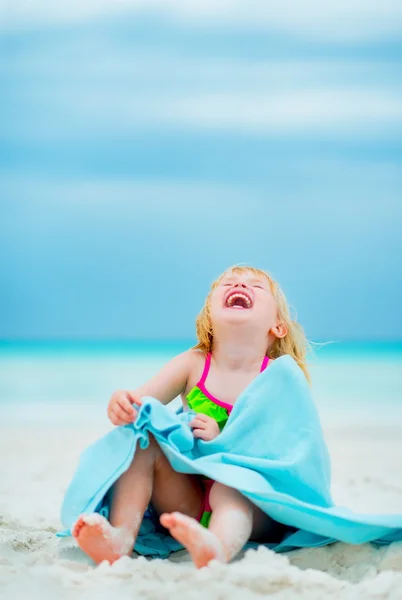 Portret roześmiany córeczkę w ręcznik siedzący na plaży — Zdjęcie stockowe